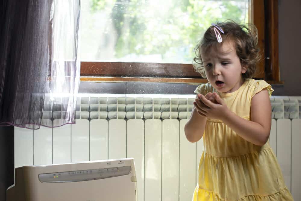 Little girl in a dusty room. Air purifier and coughing kid. Dust