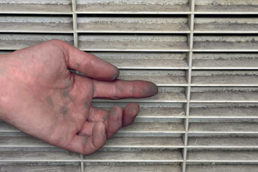 Man shows dirty hands from a dusty ventilation grill.