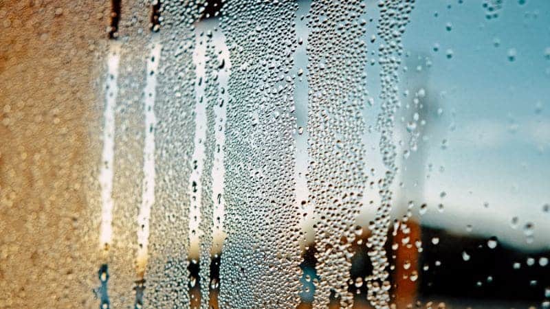 Detailný pohľad na kvapôčky vody kondenzované na sklenenom povrchu, ktoré vytvárajú rozmazaný vzor."