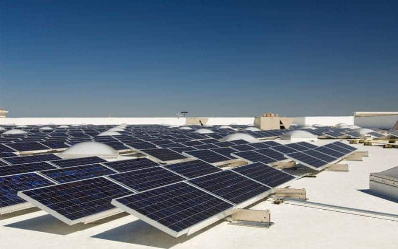 Solar panels installed on a flat rooftop against a clear blue sky.