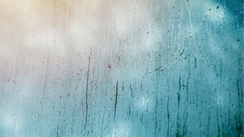 High humidity on a window with a soft focus on blurred background in blue and green tones.